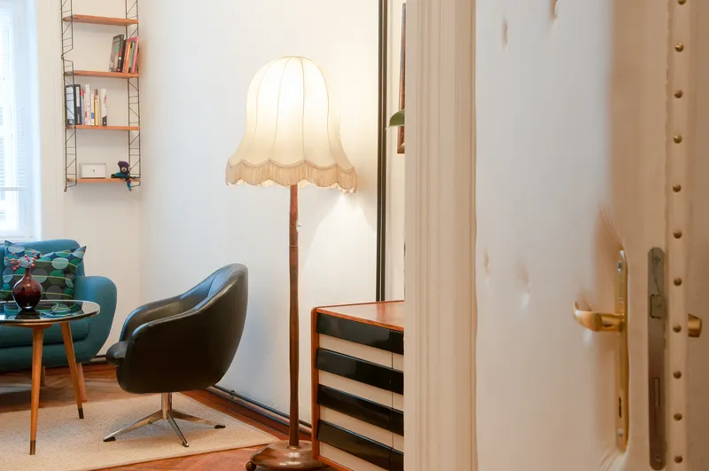 Der Blick fällt durch eine Tür in den Therapieraum. Im Raum stehen ein Stuhl und eine Bank an einem Glastisch.